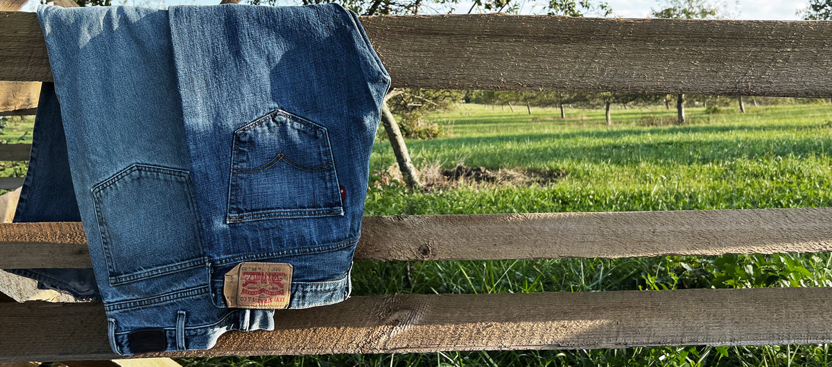 Vintage Levi’s jeans hanging over a wooden fence for the Balanced Outskirts Vol. 001 early-access page.